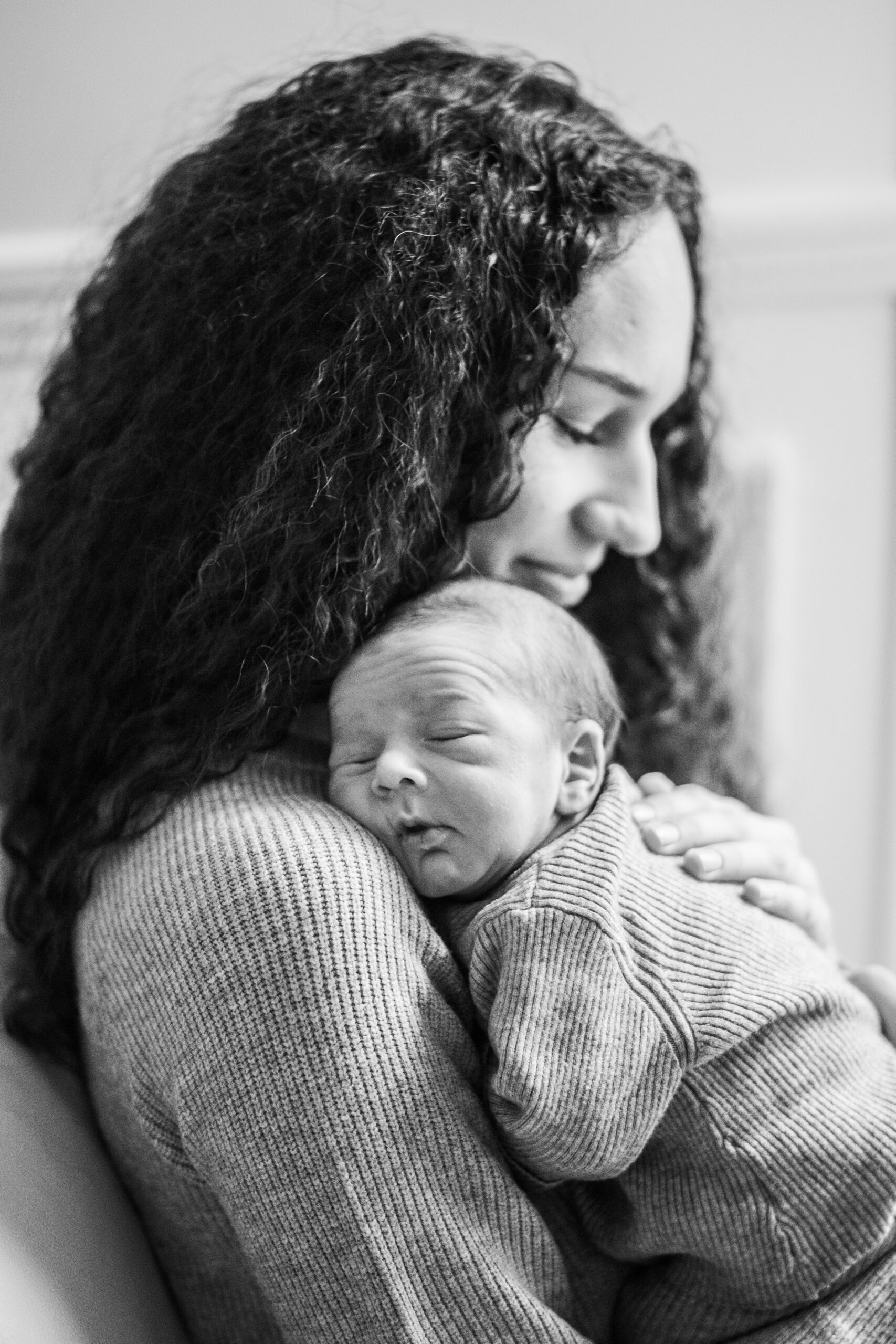 Une jeune mère tient son nouveau né de quelques mois sur son épaule en souriant
