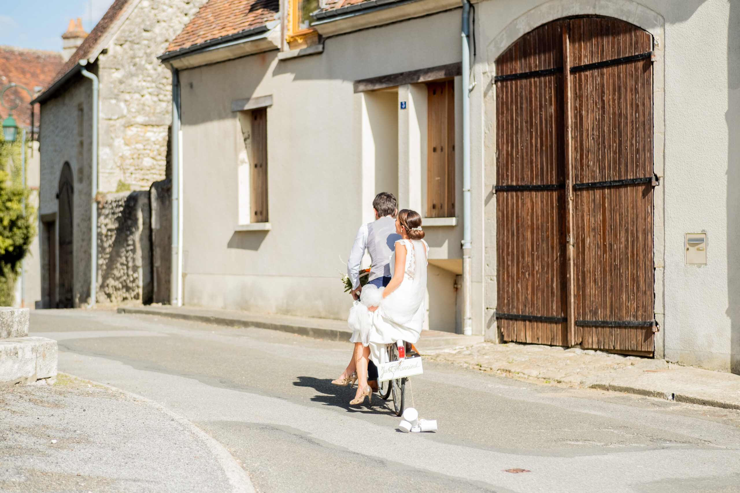 deux mariés à vélo sur une route de village